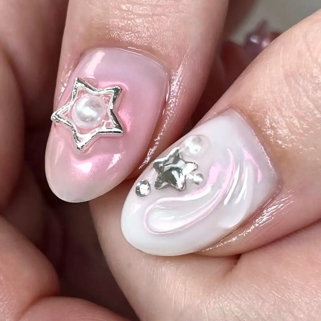 Zwei Nägel in Perlmutt-Rosa und Weiß mit silbernem Sternchen und Perle